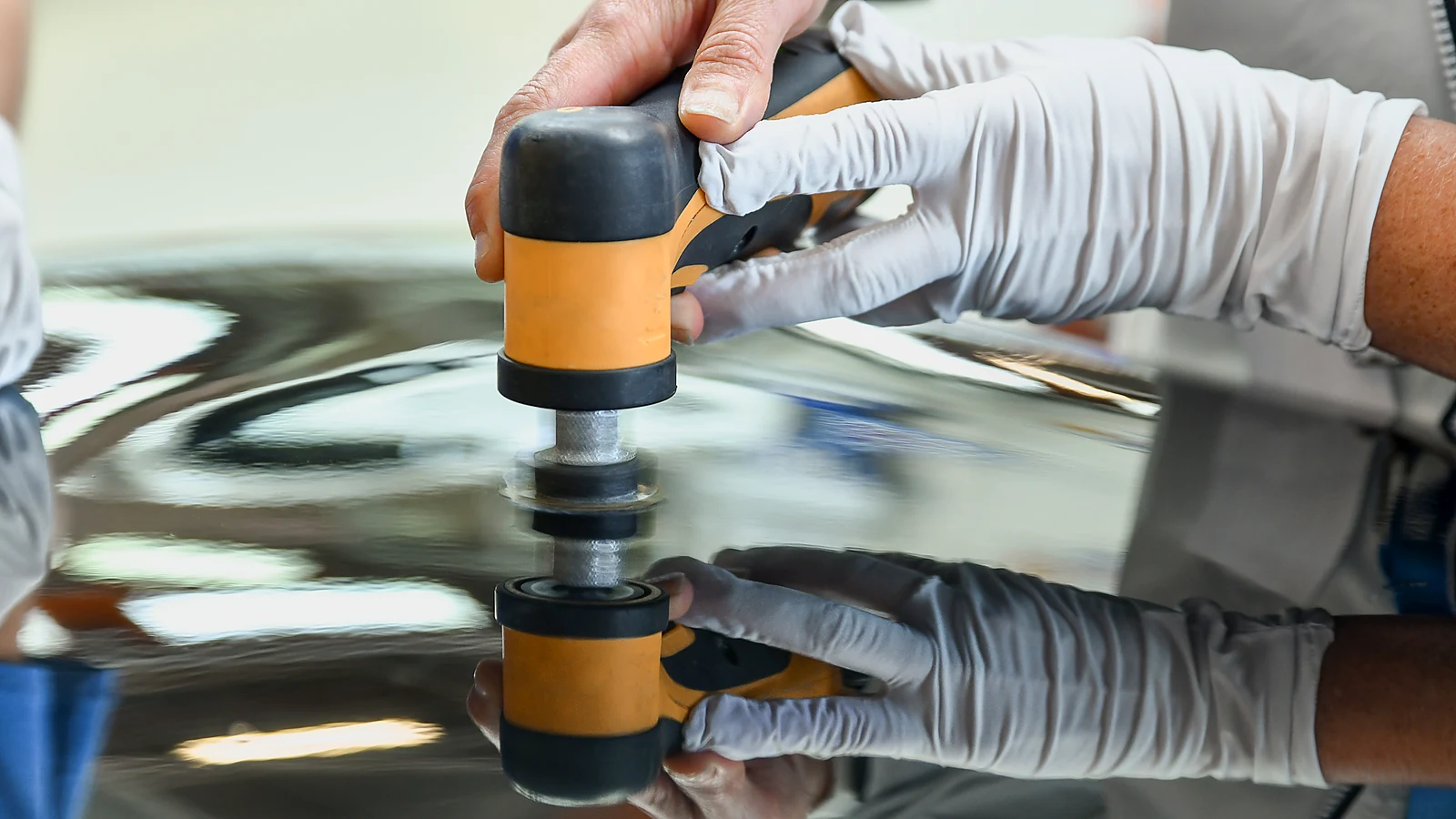 Spot repair sander on a glossy black painted panel at a finish deck